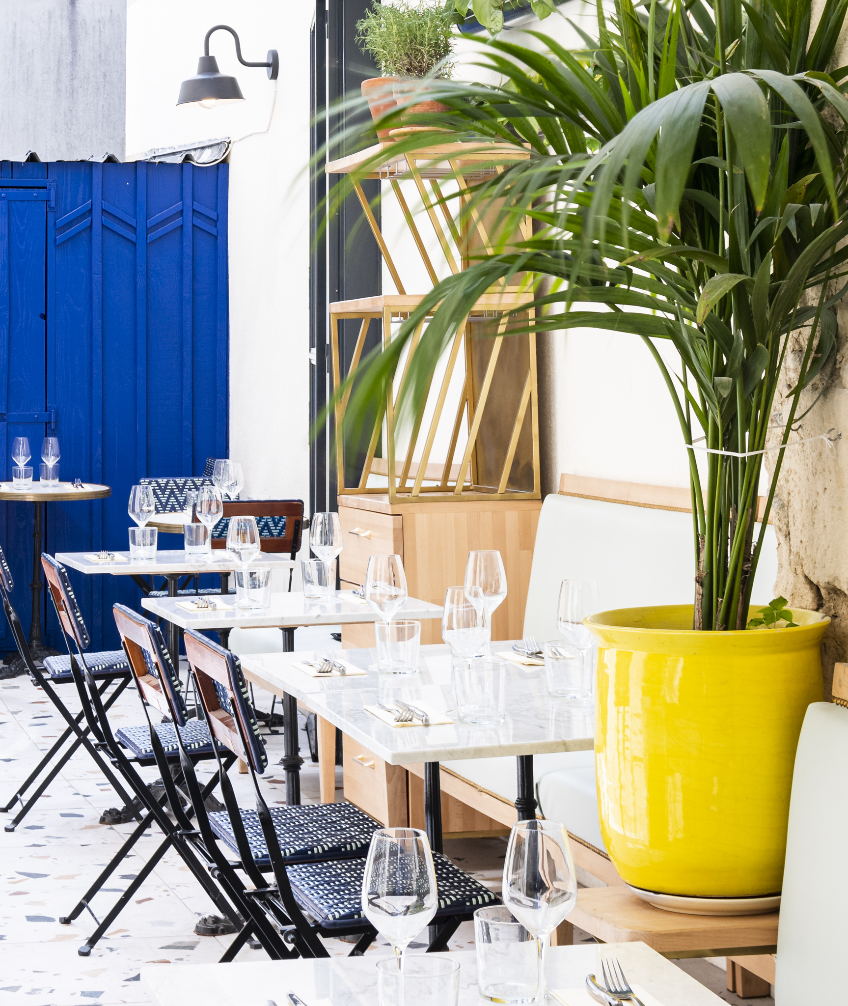 les tables dressées de la cour d'un restaurant avec une porte bleu à l'arrière