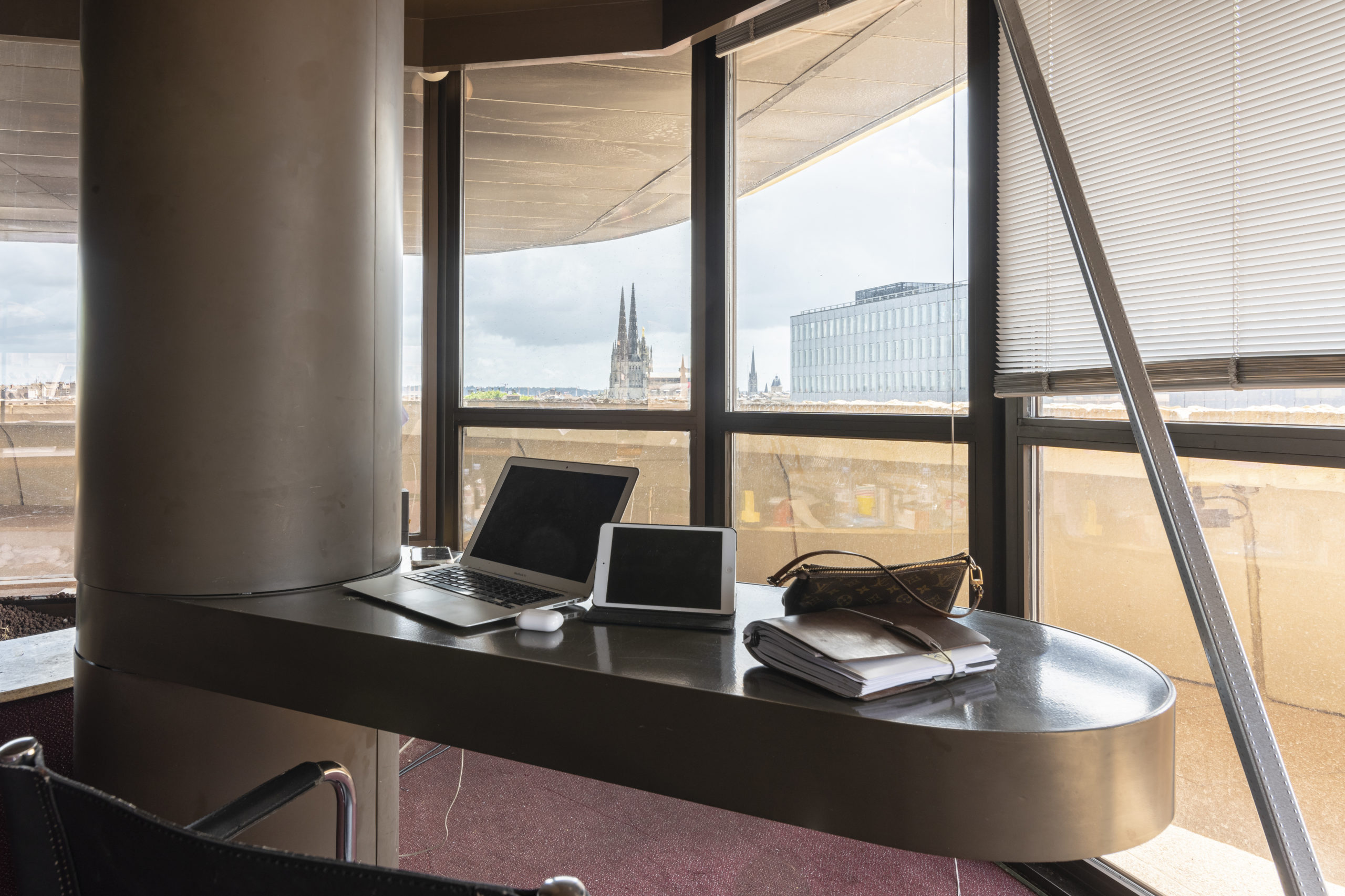 un bureau avec ordinateur face à une baie vitré de bordeaux