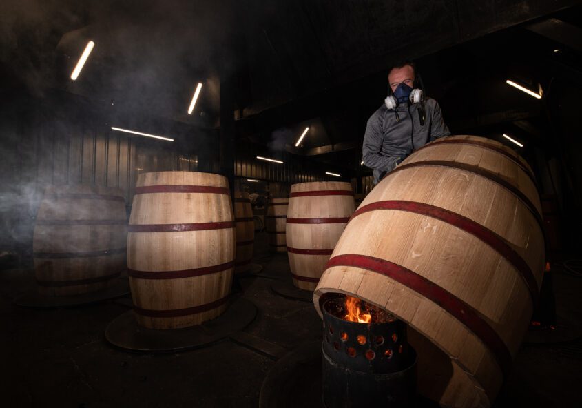 Tonnelier réalisant une chauffe sur un fût en préparation.