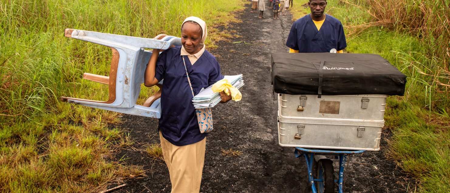 Une soeur congolaise et son aide pinassier débarque du matériel humanitaire dans la brousse pour préparer des consultations médicales.