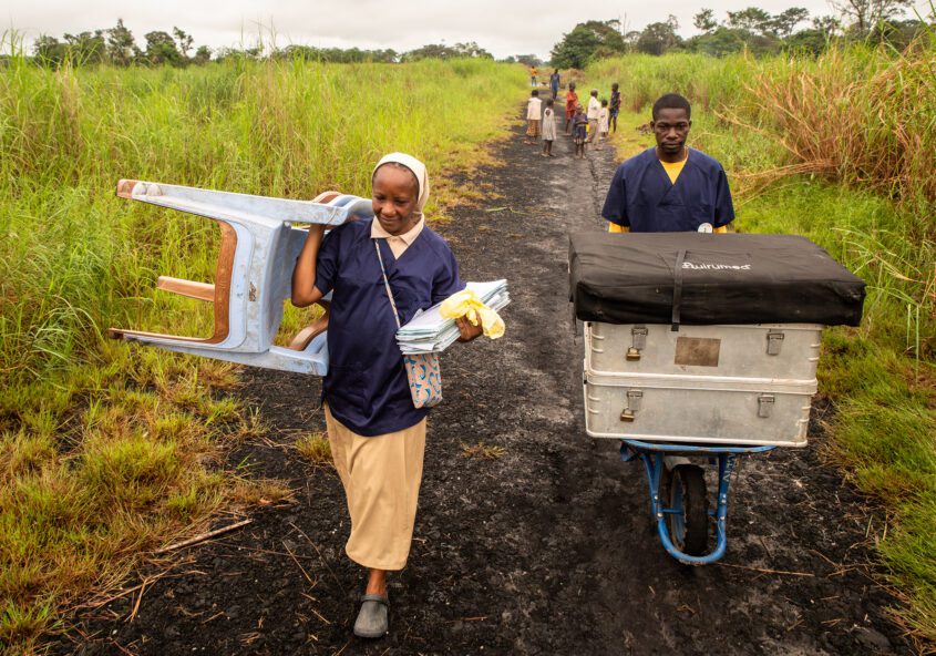 Une soeur congolaise et son aide pinassier débarque du matériel humanitaire dans la brousse pour préparer des consultations médicales.